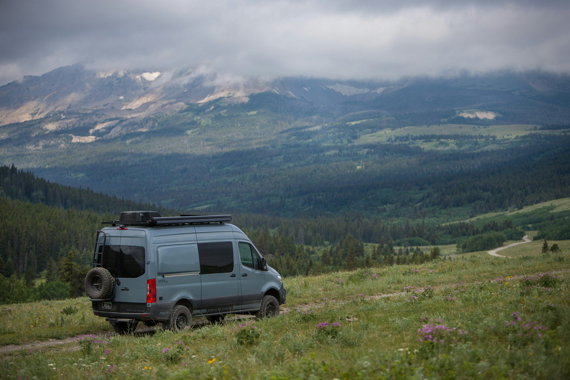 Sprinter van parked in a mountain meadow with rooftop rack